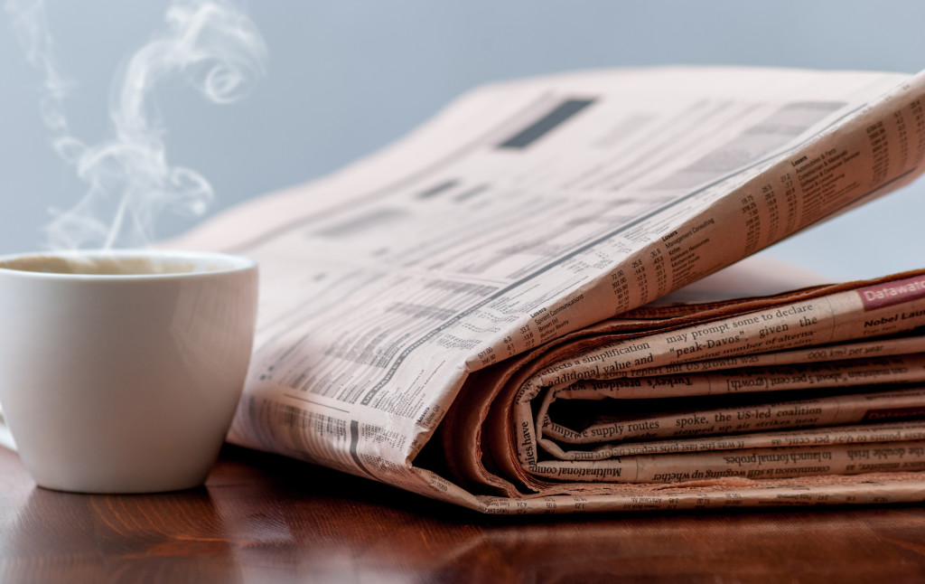 Newspaper and cup of coffee on wood table